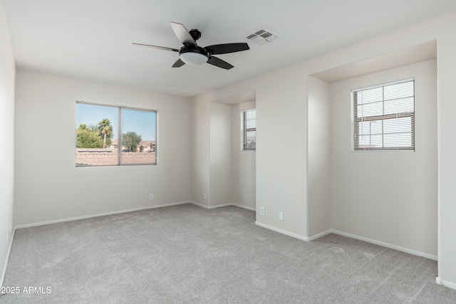 spare room with healthy amount of natural light, carpet, ceiling fan, and baseboards