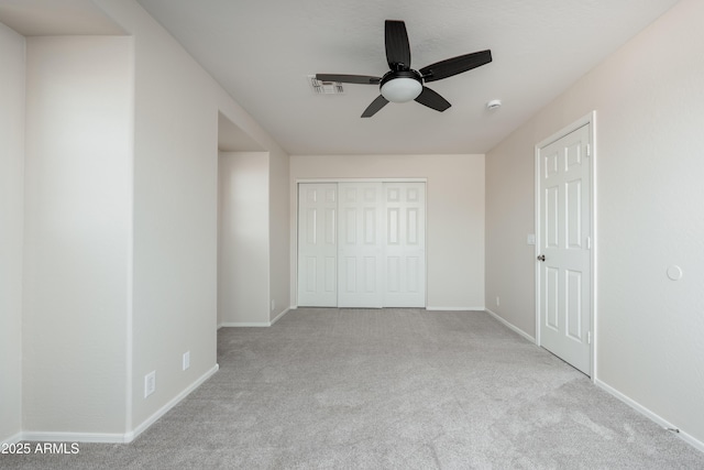 unfurnished bedroom with carpet flooring, baseboards, a closet, and a ceiling fan