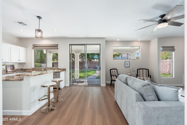 living room with light wood-type flooring, baseboards, a ceiling fan, and recessed lighting