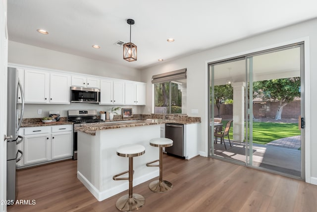 kitchen featuring stainless steel appliances, plenty of natural light, wood finished floors, white cabinets, and recessed lighting