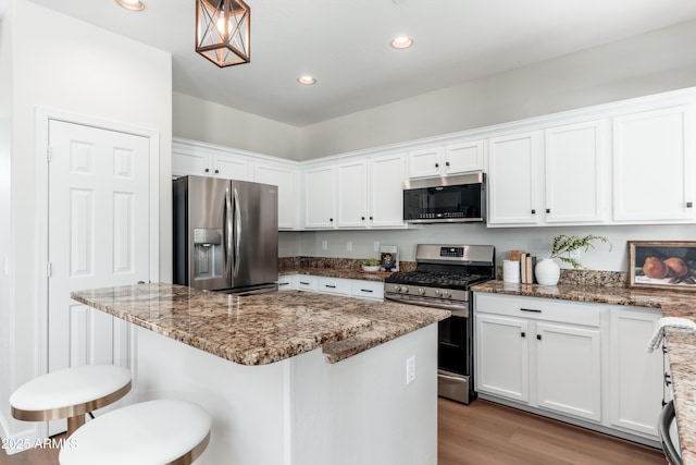 kitchen featuring stainless steel appliances, white cabinets, a kitchen island, a breakfast bar area, and light wood-style floors