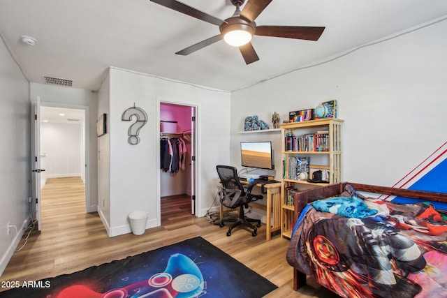 bedroom with wood-type flooring, a spacious closet, ceiling fan, and a closet