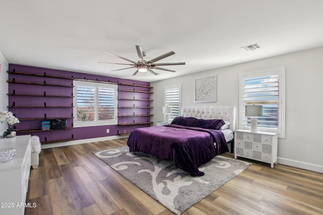 bedroom featuring hardwood / wood-style flooring, ceiling fan, and multiple windows