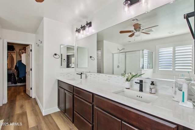 bathroom with a shower with shower door, vanity, ceiling fan, hardwood / wood-style floors, and decorative backsplash