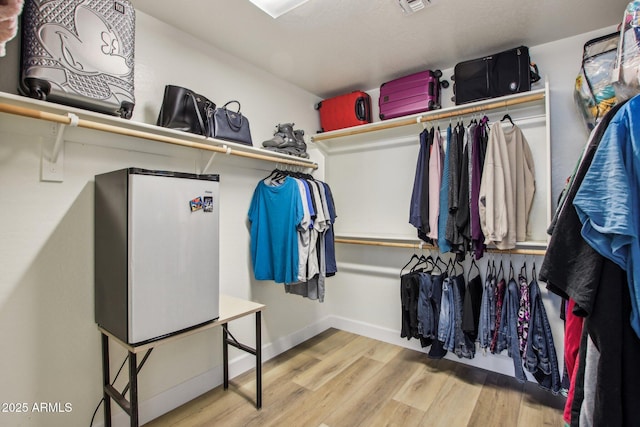 walk in closet with light hardwood / wood-style floors