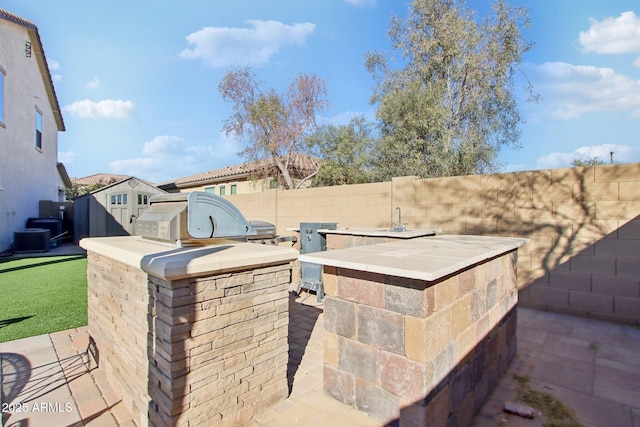 view of patio with an outdoor kitchen and central AC unit