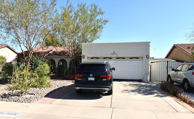 view of front of home featuring driveway, an attached garage, and stucco siding