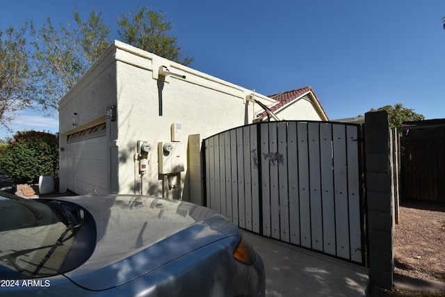 view of property exterior featuring a garage, fence, a gate, and stucco siding