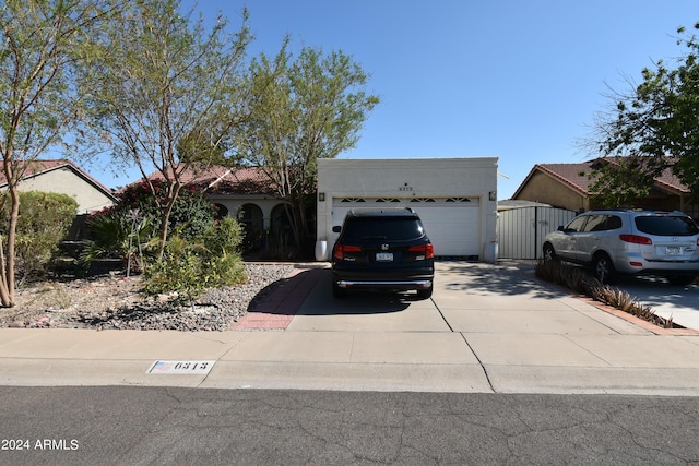 view of front of house featuring a gate, driveway, an attached garage, and stucco siding