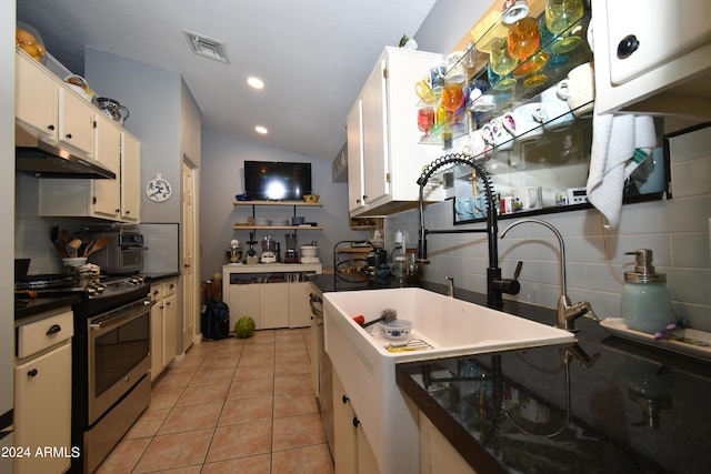 kitchen featuring stainless steel gas stove, under cabinet range hood, backsplash, and light tile patterned flooring