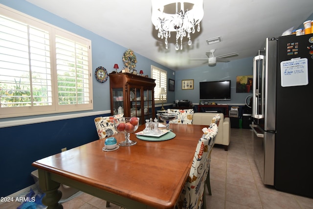 dining space with light tile patterned floors, visible vents, and ceiling fan with notable chandelier