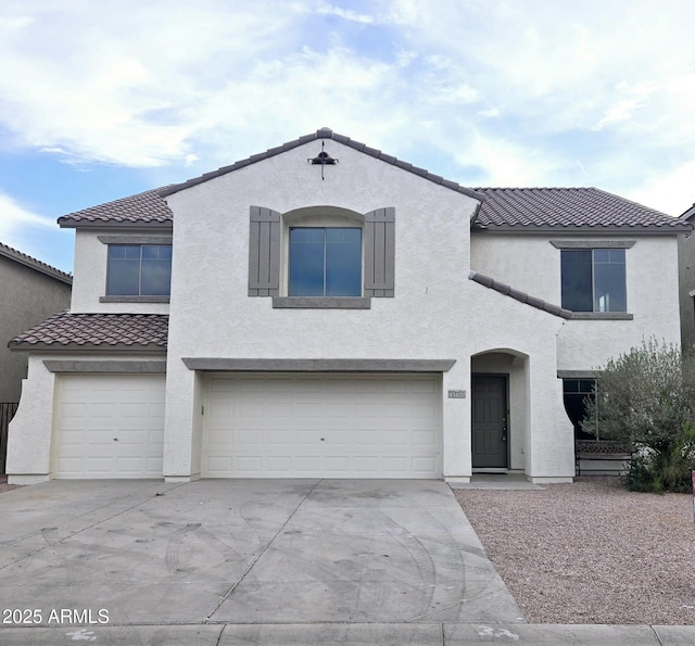 mediterranean / spanish-style home featuring a tiled roof, stucco siding, concrete driveway, and a garage