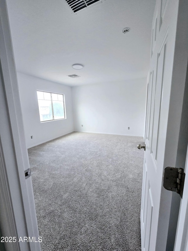 carpeted spare room featuring baseboards and visible vents
