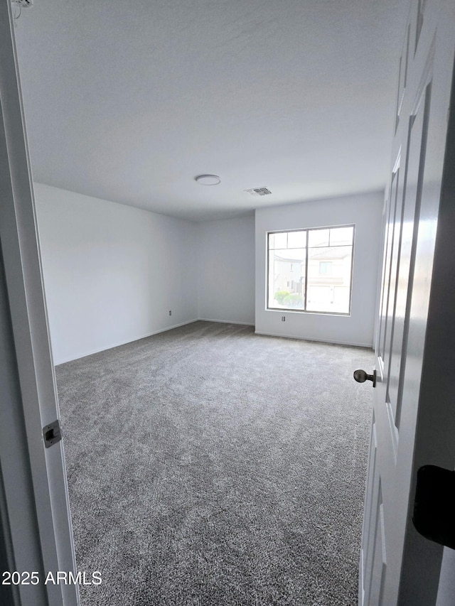 unfurnished room featuring carpet floors and visible vents