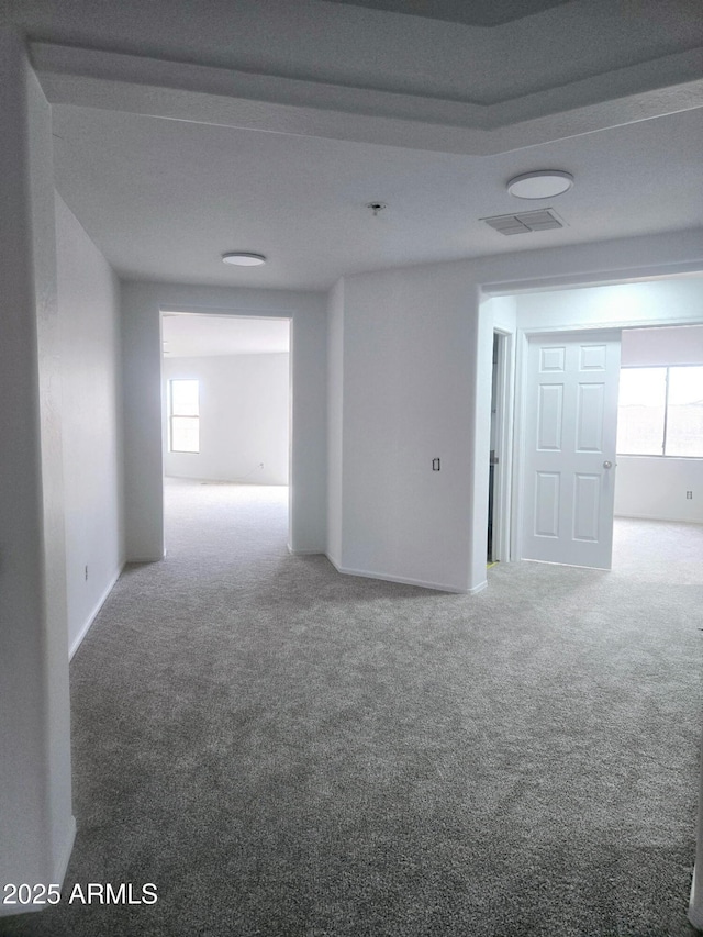 empty room with visible vents, plenty of natural light, and carpet