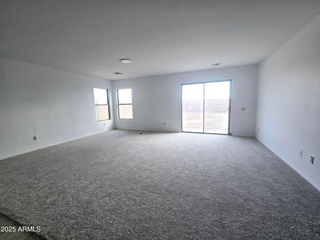 unfurnished room with carpet floors, baseboards, and visible vents