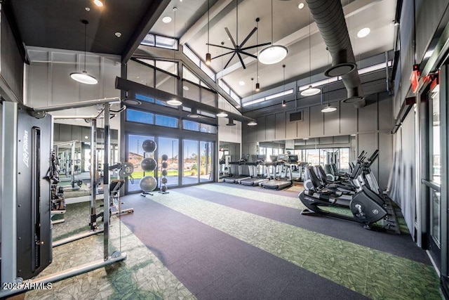workout area featuring a high ceiling, visible vents, and plenty of natural light