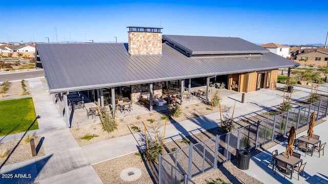 back of property with fence, outdoor dining space, a patio, and metal roof