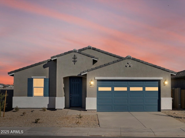 view of front of home with a tiled roof, stucco siding, concrete driveway, and a garage