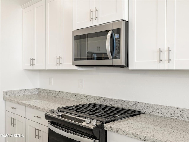 kitchen with white cabinetry, stainless steel appliances, and light stone counters