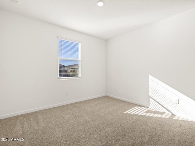 carpeted spare room featuring baseboards