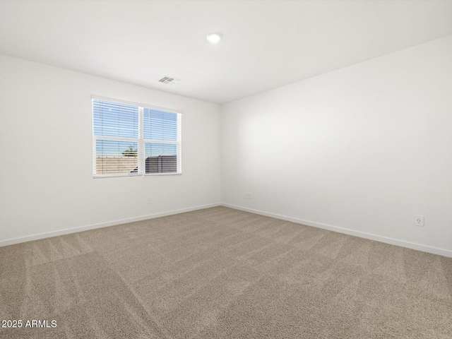spare room with baseboards, visible vents, and light carpet