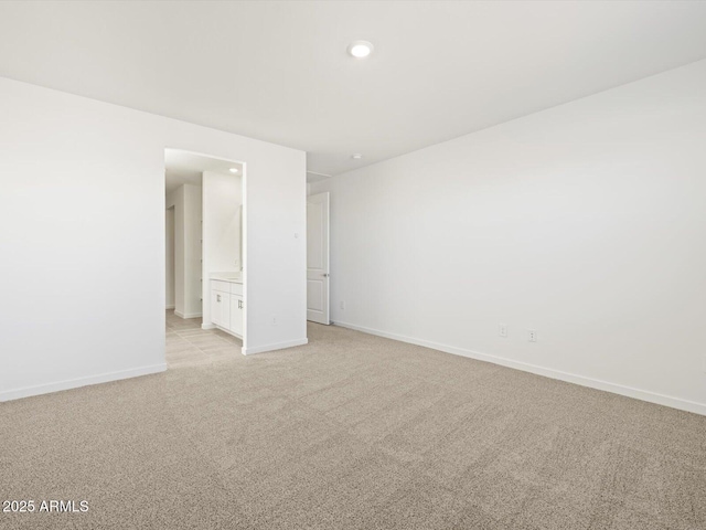 spare room featuring light colored carpet, recessed lighting, and baseboards