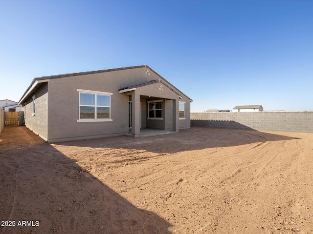 rear view of property with a fenced backyard, stucco siding, and a patio