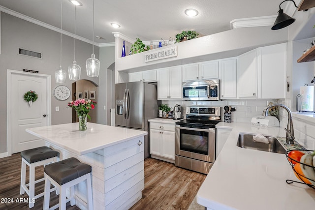 kitchen featuring white cabinetry, stainless steel appliances, sink, and a kitchen island