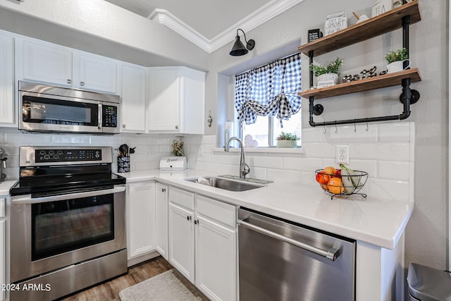 kitchen featuring sink, white cabinetry, crown molding, stainless steel appliances, and backsplash