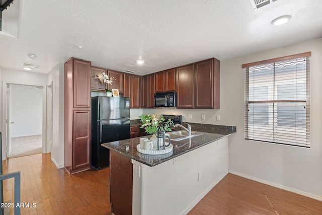 753 N Port Dr, Gilbert, AZ 85233 - kitchen with black appliances, a peninsula, baseboards, wood finished floors, and recessed lighting