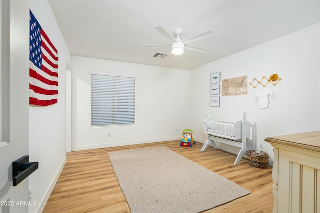 bedroom featuring baseboards, a ceiling fan, visible vents, and light wood-style floors