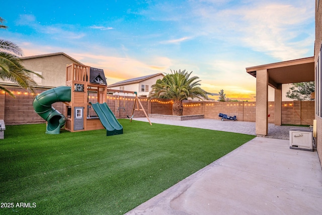 playground at dusk featuring a patio, a yard, a playground, and a fenced backyard