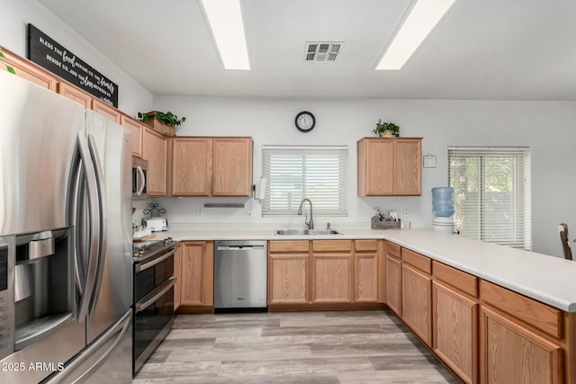 kitchen featuring stainless steel appliances, a peninsula, a sink, visible vents, and a wealth of natural light