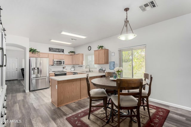 kitchen featuring arched walkways, stainless steel appliances, light countertops, visible vents, and a sink