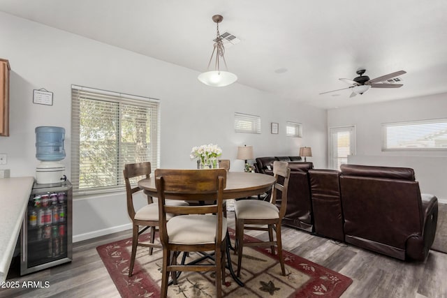 dining area featuring ceiling fan, wine cooler, wood finished floors, visible vents, and baseboards