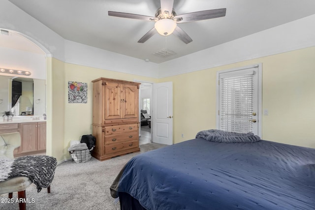 bedroom with arched walkways, carpet flooring, visible vents, and ensuite bathroom