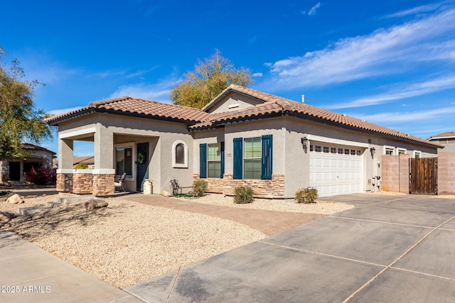 mediterranean / spanish house with concrete driveway, stone siding, a tile roof, an attached garage, and stucco siding