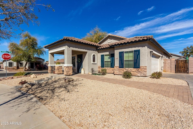mediterranean / spanish-style home with a garage, stone siding, a tile roof, and stucco siding
