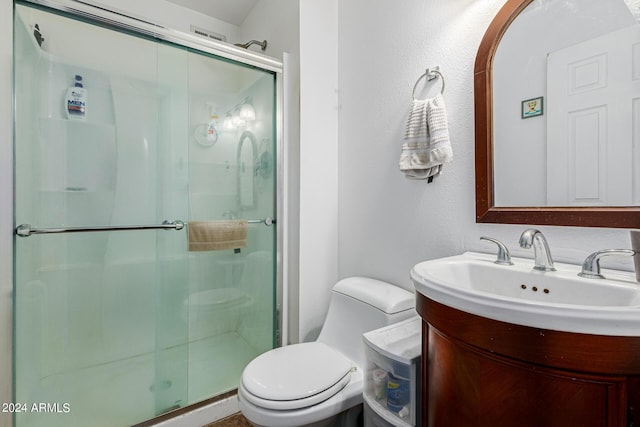 bathroom featuring vanity, toilet, and a shower with door