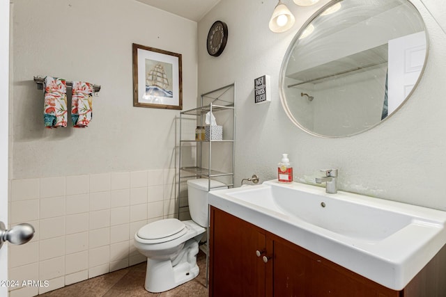 bathroom with tile patterned flooring, vanity, tile walls, and toilet