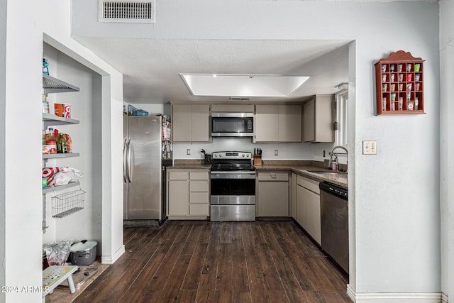 kitchen with gray cabinetry, sink, dark hardwood / wood-style floors, a textured ceiling, and appliances with stainless steel finishes