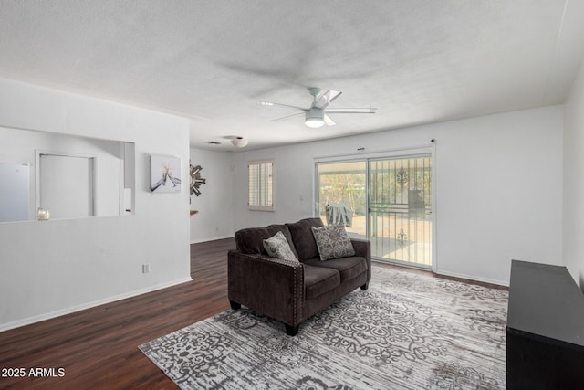 living room with a textured ceiling, wood finished floors, a ceiling fan, and baseboards