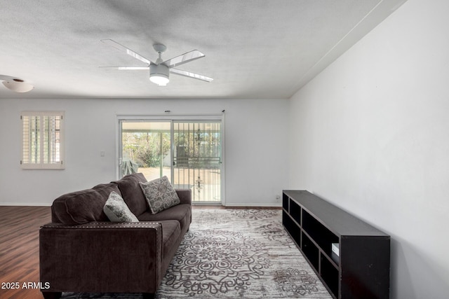 living area featuring ceiling fan, a textured ceiling, baseboards, and wood finished floors