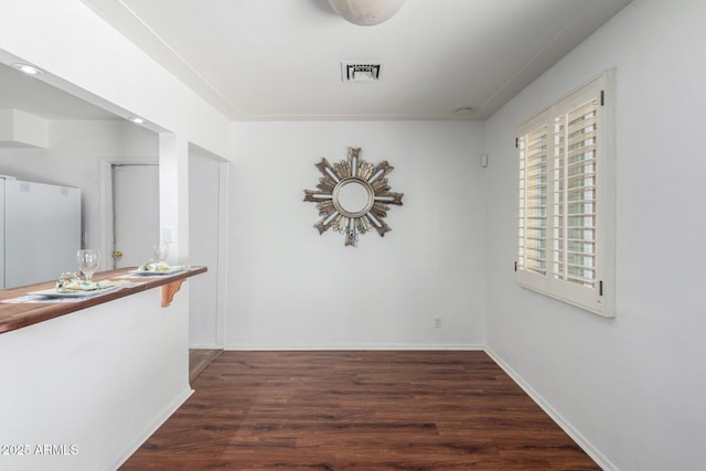 corridor with wood finished floors, visible vents, and baseboards