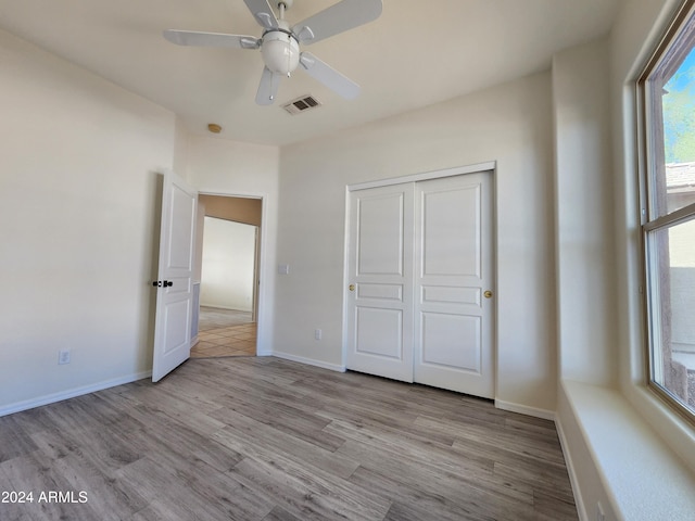 unfurnished bedroom with ceiling fan, light hardwood / wood-style floors, and a closet