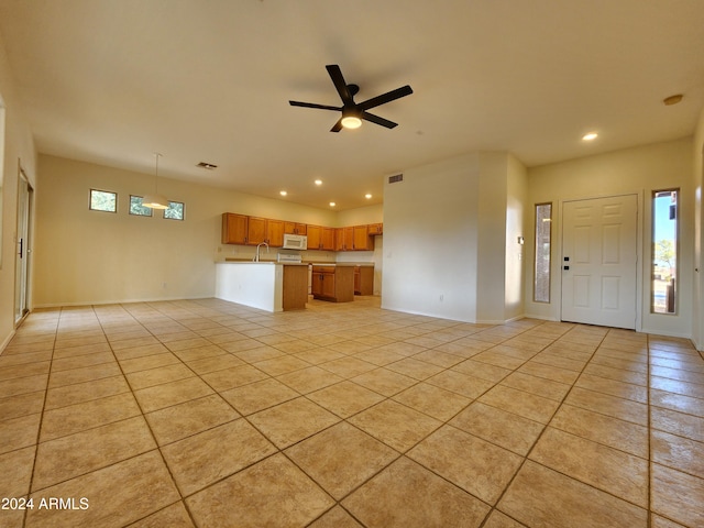 unfurnished living room featuring sink, ceiling fan, and light tile patterned flooring