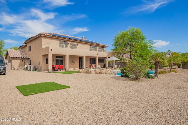 24916 N 80th Ln, Peoria, AZ 85383 - back of property featuring central air condition unit, roof mounted solar panels, a patio area, stucco siding, and an outdoor pool