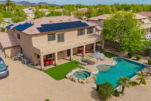 24916 N 80th Ln, Peoria, AZ 85383 - back of house with stucco siding, solar panels, a patio, a mountain view, and a pool with connected hot tub