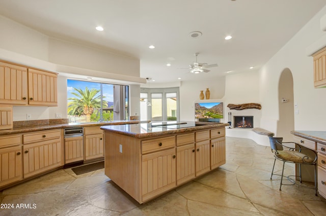 kitchen with a center island, light brown cabinets, electric cooktop, a kitchen breakfast bar, and ceiling fan